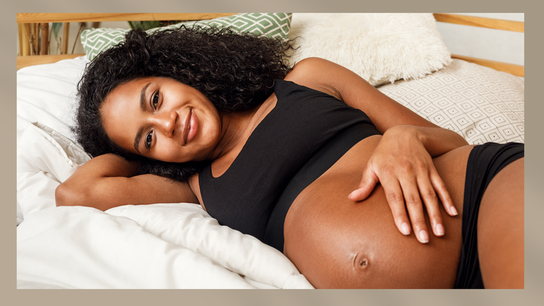 Picture of a pregnant person lying on their side on a comfy bed like you'd find at a birth center.