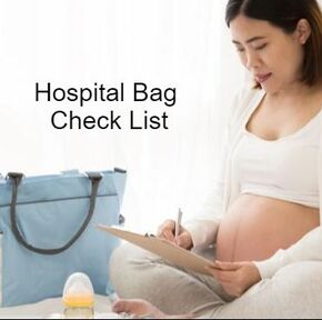 Pregnant person sitting on a bed reviewing their hospital bag check list with their hospital bag next to them